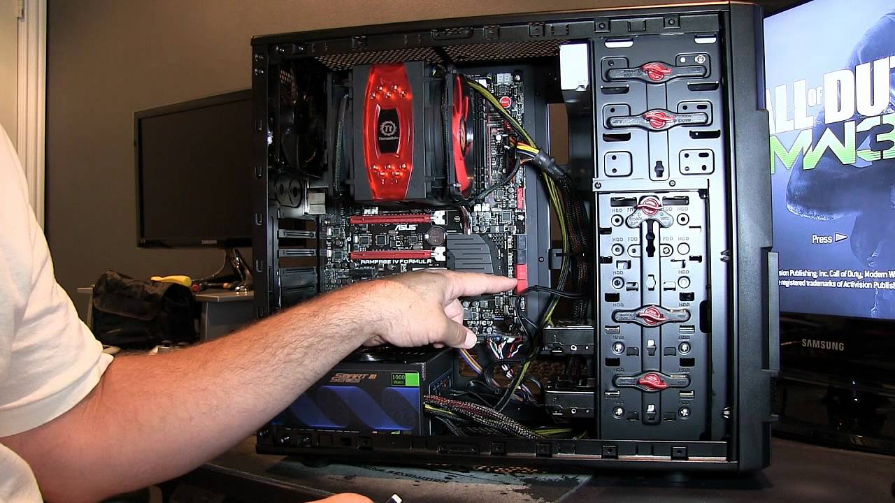 A technician adjusting components on an open gaming PC motherboard rig under studio conditions